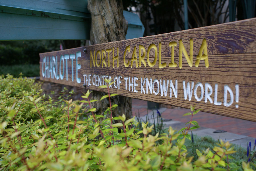 A sign post stating the Charlotte NC is the Center of the Known World! 